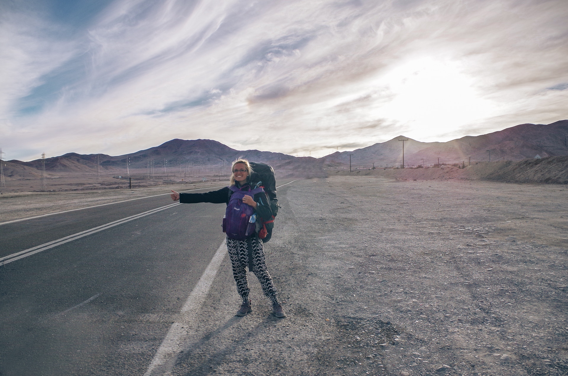 femme au bord d'une route au Chili en train de faire du stop