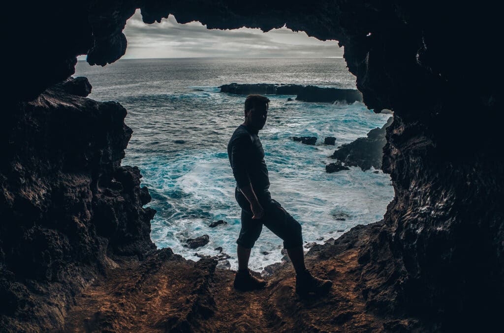 silhouette d'un homme dans une grotte avec vue sur l'océan