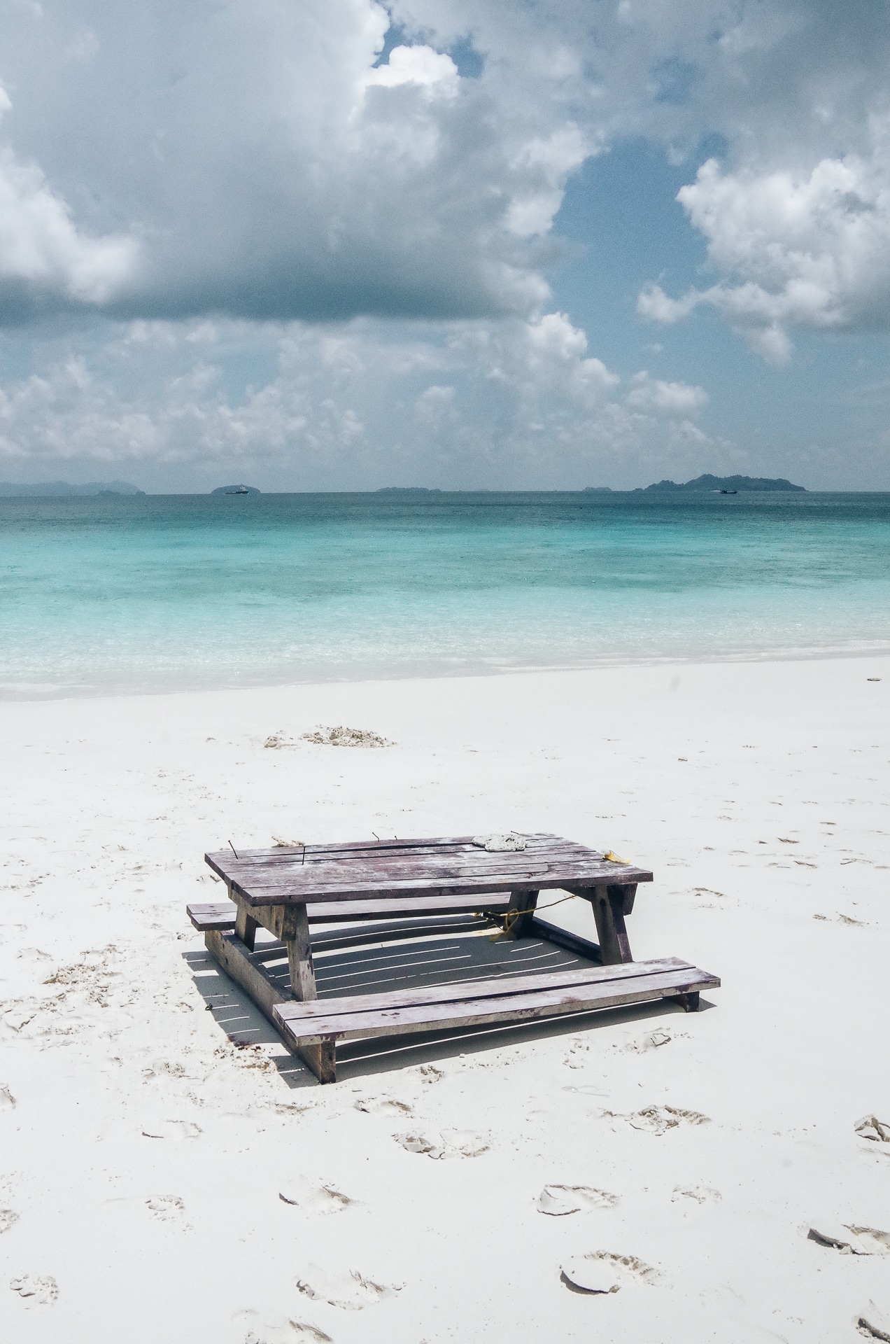 table et banc en bois installé face à la mer sur une plage de sable blanc Kawthaung
