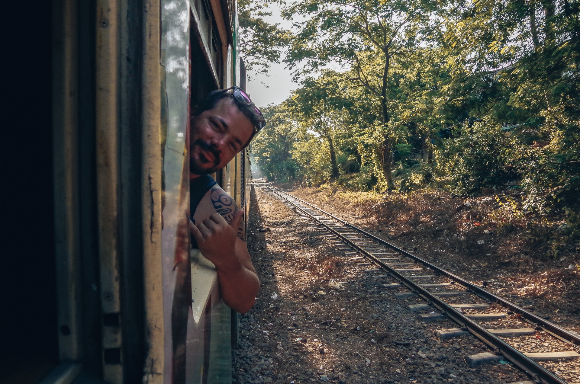 homme faisant coucou à travers une fenêtre d'un train au Myanmar