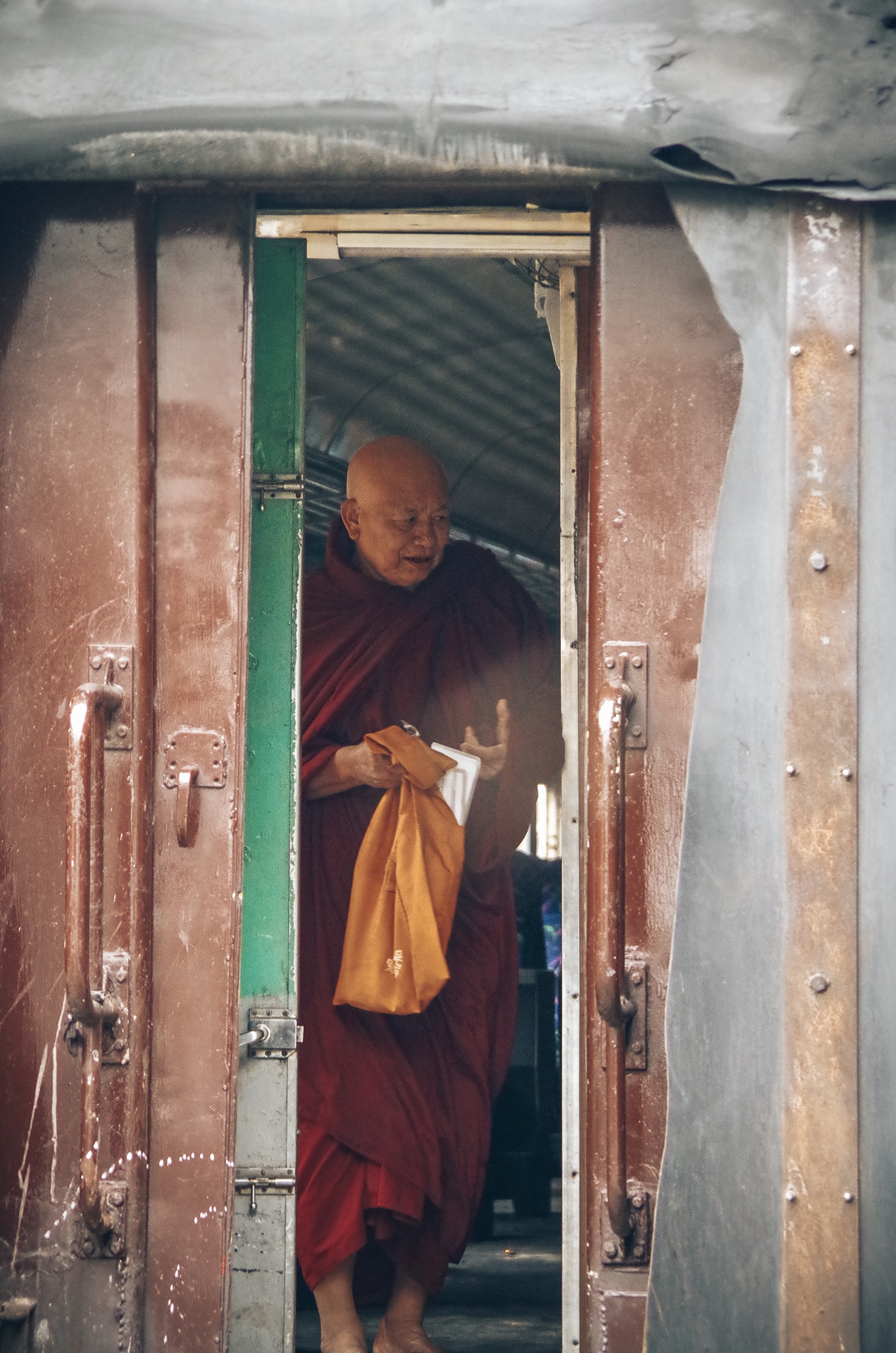 portrait d'un moine bouddhiste dans l'entrebâillement d'une porte de train
