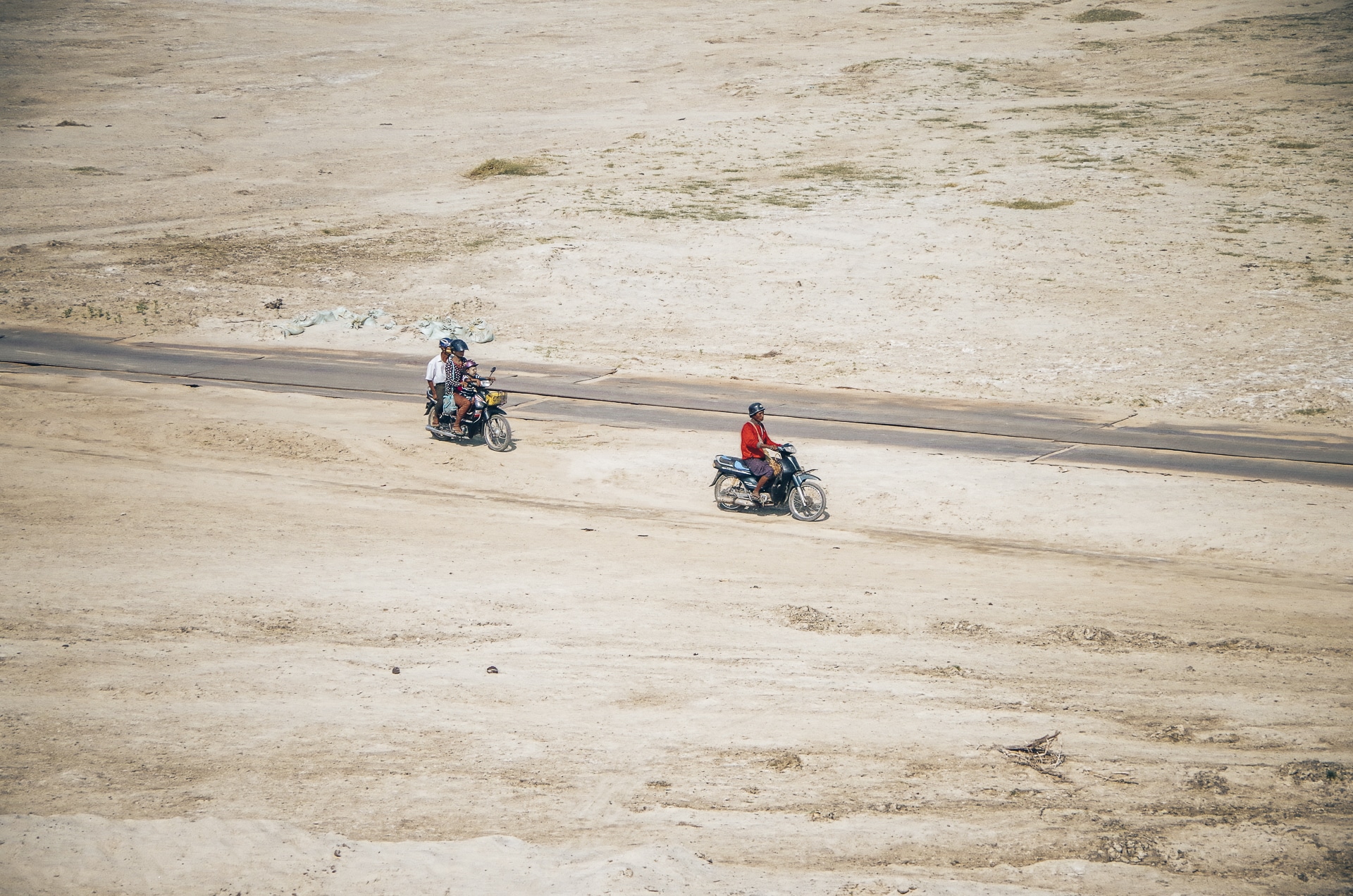 birmans conduisant des scooters sur une route de sable au Myanmar