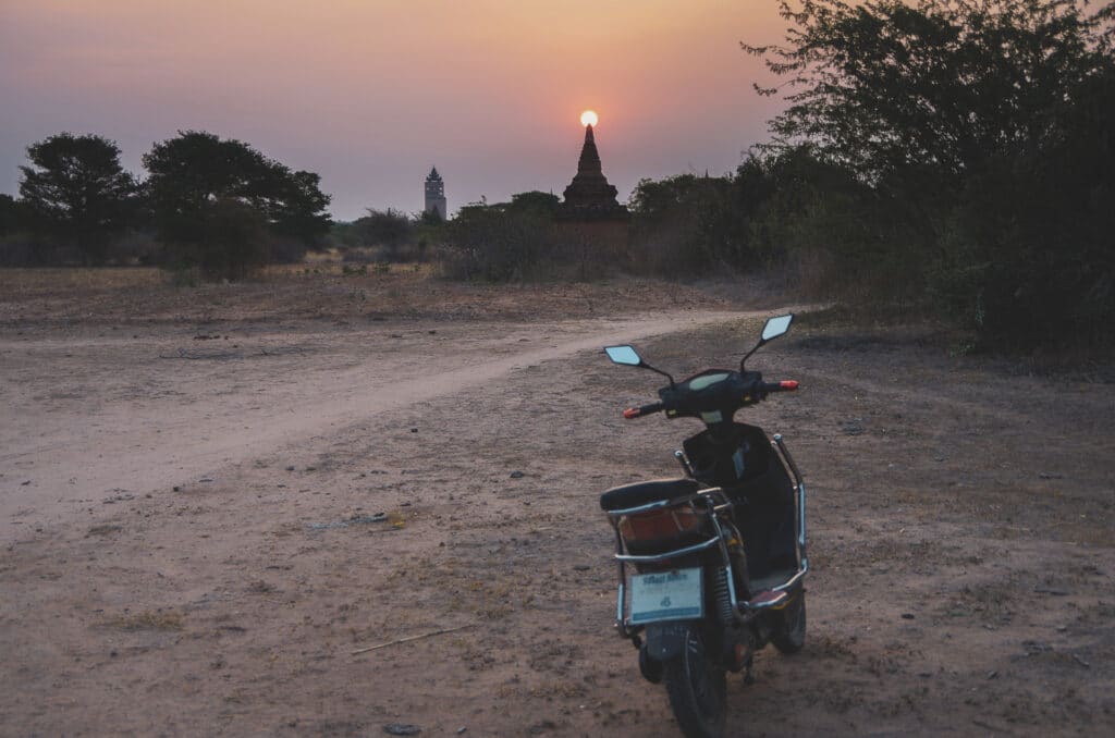 scooter garé face à un coucher de soleil sur les temples de Bagan visiter Myanmar
