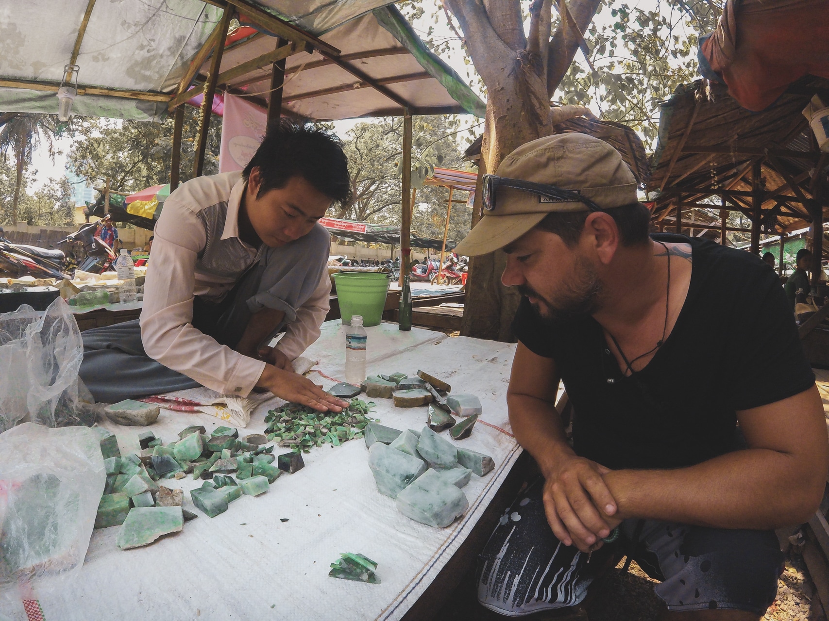 homme qui regarde des morceaux de jade brut auprès d'un vendeur à Mandalay