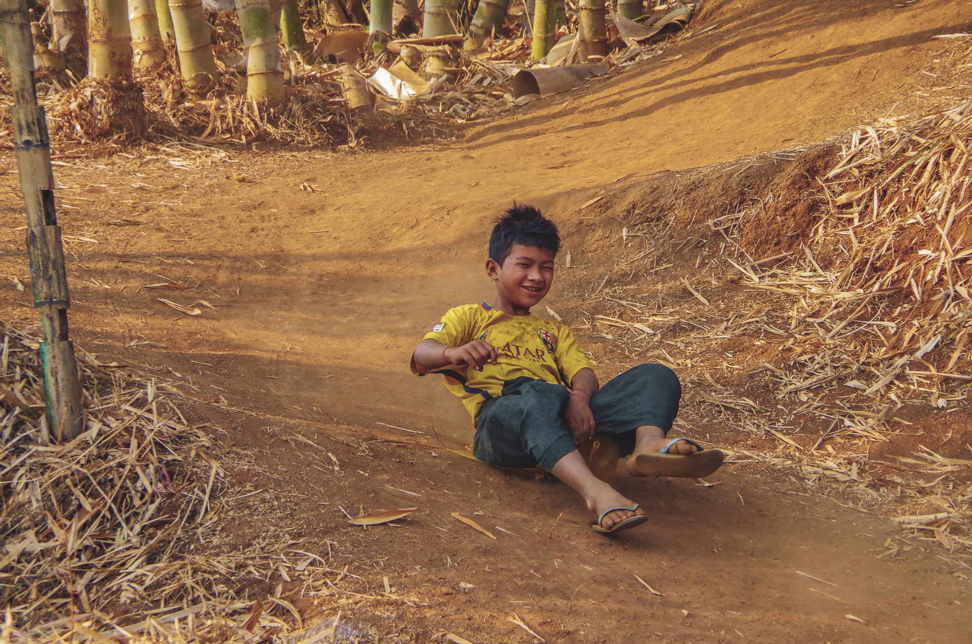 enfant faisant de la luge sur un morceau de plastique Myanmar Trek Kalaw Inle