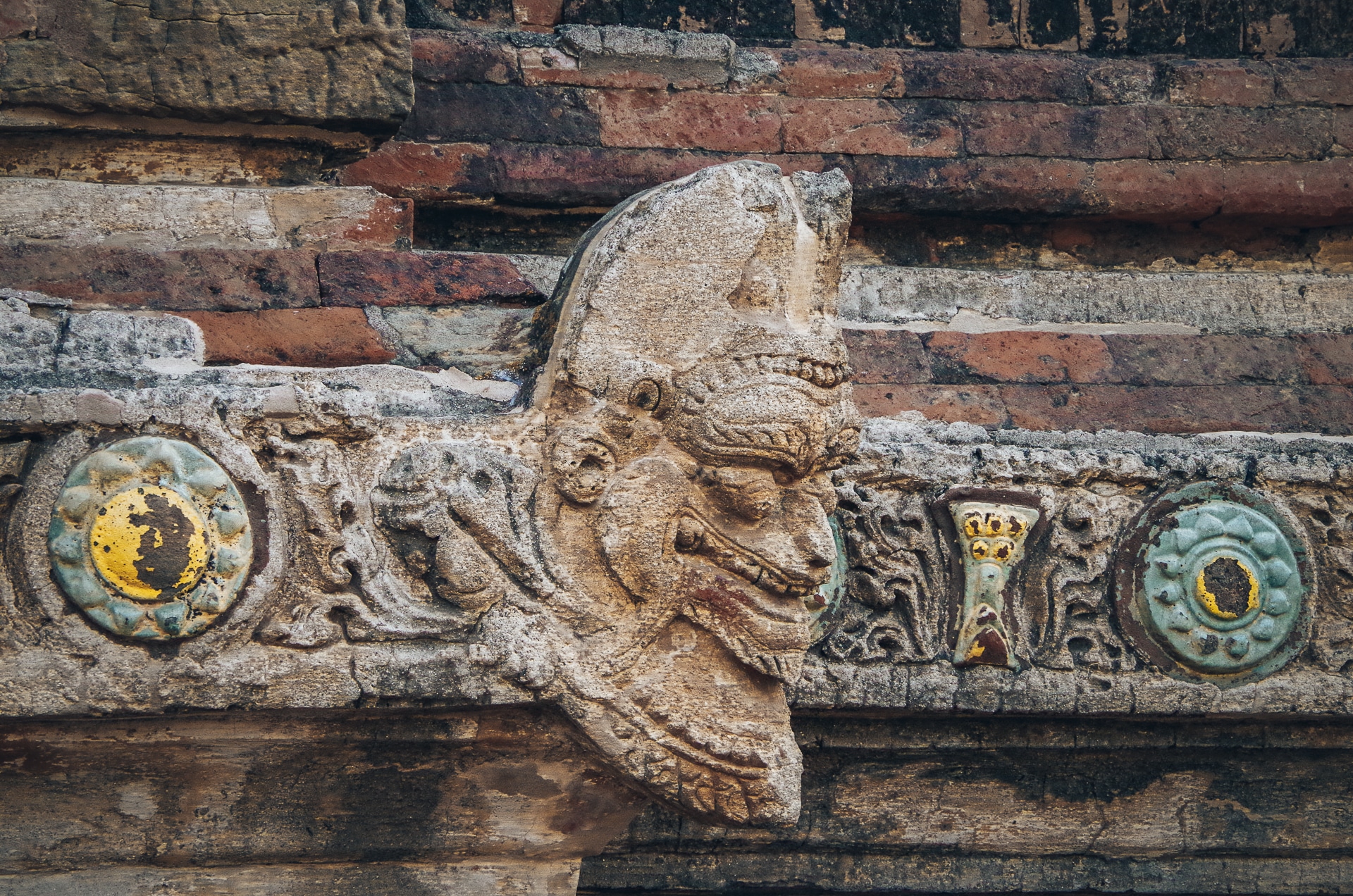 sculpture d'une tête sur une frise avec de la céramique sur un temple de Bagan